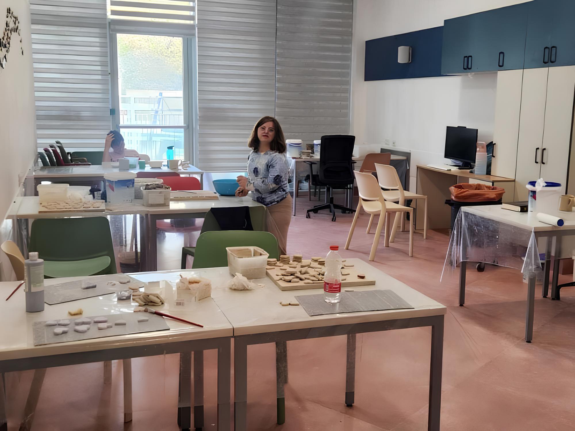 מתחם לסדנאות תעסוקה, חדר עם שולחנות ובחורה עם מוגבלות